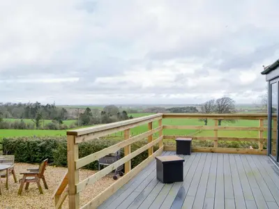 a deck with a table and chairs and a fence at The Coach House in Blencogo