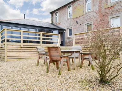 a picnic table and two chairs in front of a building at The Coach House in Blencogo