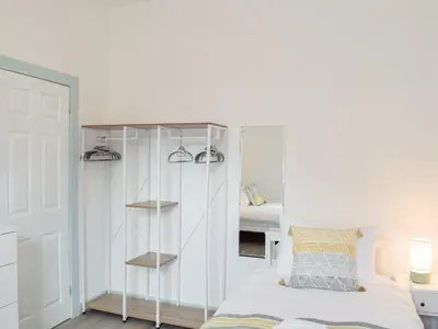 a bedroom with a white cabinet and a bed at Miners Cottage in Girvan