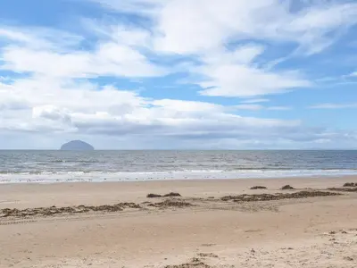 a sandy beach with a view of the ocean at Miners Cottage in Girvan