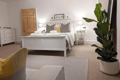 a white bedroom with a white bed and a plant at Townhouse Apartment Carlisle in Carlisle