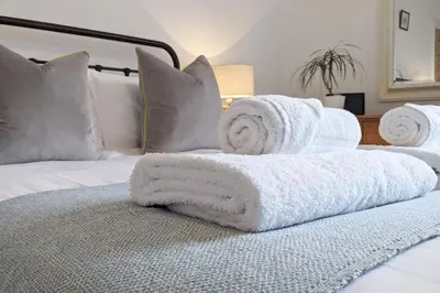 a pile of towels sitting on top of a bed at Townhouse Apartment Carlisle in Carlisle