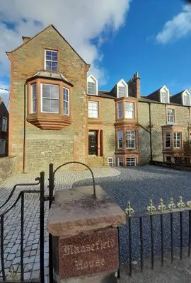 a large brick house with a sign in front of it at Kirkcudbright Holiday Apartments - Apartment E in Kirkcudbright