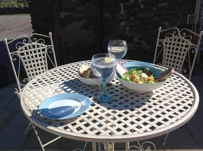 a white table with a bowl of salad and wine glasses at The Hayloft. Entire Barn Conversion near Keswick in Applethwaite