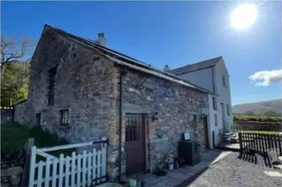 an old stone house with a white fence and a building at The Hayloft. Entire Barn Conversion near Keswick in Applethwaite
