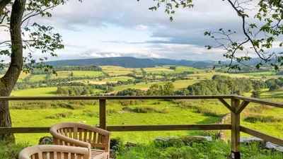 two chairs sitting on a balcony looking out over a valley at Snowdrop, Penruddock an Eco and dog friendly lodge with hot tub, 10 minutes to Lake Ullswater in Penruddock