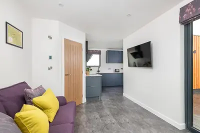 a living room with a purple couch and a kitchen at Snowdrop, Penruddock an Eco and dog friendly lodge with hot tub, 10 minutes to Lake Ullswater in Penruddock