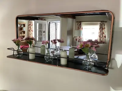 a mirror on a wall with vases of flowers and candles at Porch Cottage, a luxurious characterful cottage within walking distance of Keswick town centre in Keswick