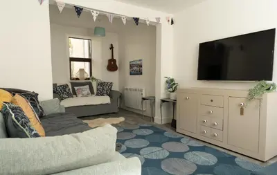 a living room with a couch and a flat screen tv at The Portpatrick Pad - A cosy 3 bed cottage, w. sea views & garden office in Portpatrick