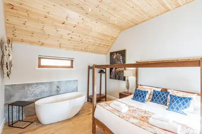 a bedroom with a bath tub and a bed at Kestrel Lodge 2 with Hot Tub in Newton Stewart