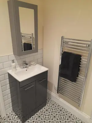 a bathroom with a sink and a mirror and a shower at Kirkcudbright Holiday Apartments - Apartment C in Kirkcudbright