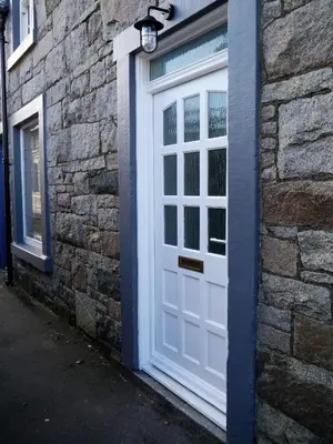 a white door on the side of a brick building at Stroan in New Galloway