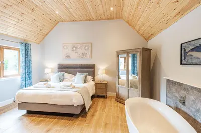 a bedroom with a bed and a bath tub at Osprey Lodge 1 with Hot Tub in Newton Stewart