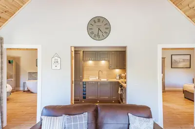 a living room with a couch and a clock on the wall at Osprey Lodge 1 with Hot Tub in Newton Stewart
