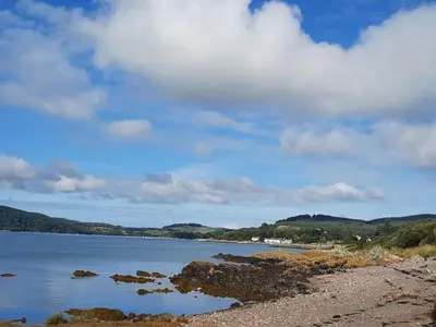 a body of water with rocks on the shore at Foxbrae Cottage in Rockcliffe