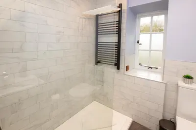 a white bathroom with a tub and a window at 1 Bridge Syke Elterwater in Ambleside