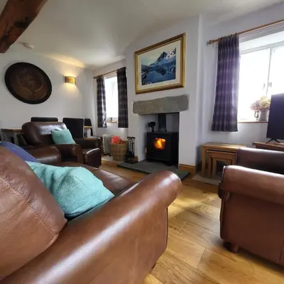 a living room with a leather couch and a fireplace at 1 Bridge Syke Elterwater in Ambleside