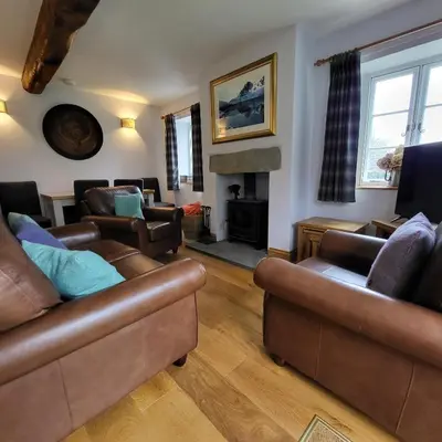 a living room with leather furniture and a fireplace at 1 Bridge Syke Elterwater in Ambleside