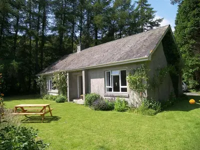 a small house with a picnic table in a yard at Glenauld Cottage in Kirkcudbright