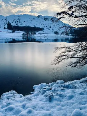 a lake covered in snow with mountains in the background at The Grasmere Hotel in Grasmere