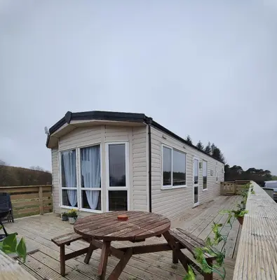 a tiny house with a picnic table on a deck at Just Resort No29 in Balminnoch
