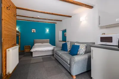 a living room with a couch and a bed at Cosy Glamping In the Eskdale Valley - Studio Lodges and Mega Pods in Eskdale