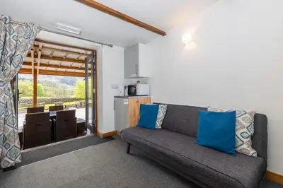 a living room with a couch and a kitchen at Cosy Glamping In the Eskdale Valley - Studio Lodges and Mega Pods in Eskdale