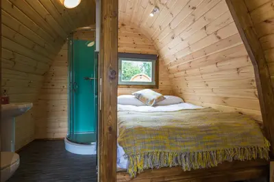 a bed in a wooden room with a window at Cosy Glamping In the Eskdale Valley - Studio Lodges and Mega Pods in Eskdale