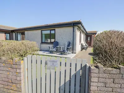 a house with a fence and chairs in the yard at Seaspray in St Bees