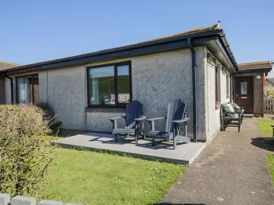 a patio with two chairs and a table in front of a house at Seaspray in St Bees