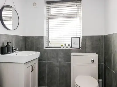 a bathroom with a toilet and a sink and a mirror at Wainwright Cottage in Seascale