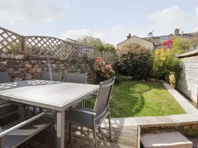 a patio with a table and chairs in a garden at Wainwright Cottage in Seascale