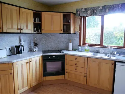 a kitchen with wooden cabinets and a sink and a window at Collin Hill House in Castle Douglas
