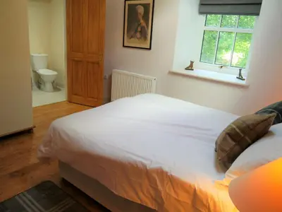 a bedroom with a white bed and a window at Rusko Stables in Gatehouse of Fleet