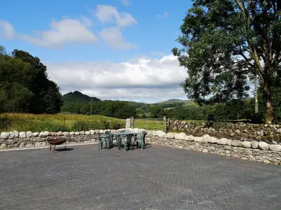 a table and chairs in a patio with a stone wall at Rusko Stables in Gatehouse of Fleet