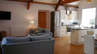 a living room with two couches and a kitchen at Rusko Stables in Gatehouse of Fleet