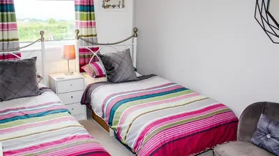 a bedroom with two beds and a chair and a window at Spacious Holiday Home in Cumbria in Arlecdon