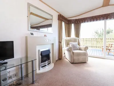 a living room with a fireplace and a chair and a television at Whiteside in Cockermouth