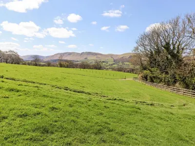 a green field with a fence and mountains in the background at Whiteside in Cockermouth