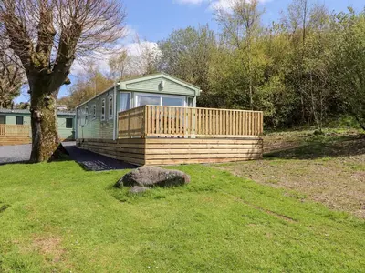 a green house with a wooden deck in a yard at Whiteside in Cockermouth