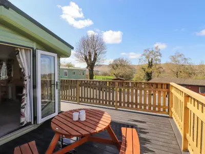 a wooden deck with a wooden table and chairs at Swinside in Cockermouth