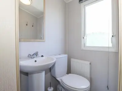 a bathroom with a toilet and a sink and a window at Swinside in Cockermouth