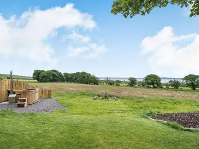 a large grassy field with a wooden fence at The Curve At Caerlaverock Estate in Glencaple