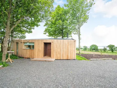 a wooden house with a metal roof at The Curve At Caerlaverock Estate in Glencaple