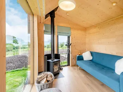 a living room with a blue couch and a stove at The Curve At Caerlaverock Estate in Glencaple