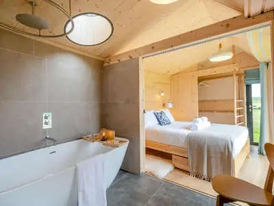 a bathroom with a tub and a bed in a room at The Curve At Caerlaverock Estate in Glencaple
