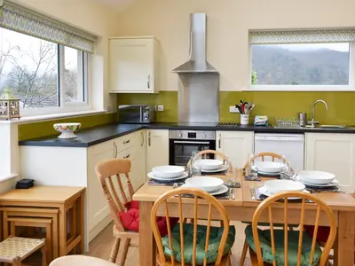 a kitchen with a wooden table and chairs and a kitchen with a stove at Brow Riding in Keswick