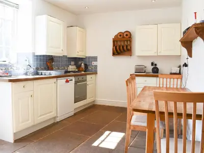 a kitchen with white cabinets and a wooden table at Rushgill House in Sebergham