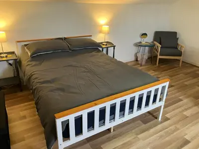 a large bed in a room with two tables and a chair at Bells yard Cottage Maryport in Maryport
