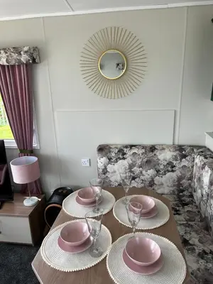 a table with plates and glasses and a mirror at Marianne Bay - Southerness Caravan Park with Sea View - Pet Friendly in Mainsriddle